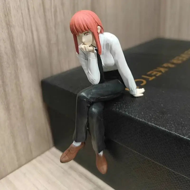 A detailed 14cm pvc chainsaw man makima noodle stopper figure with vibrant red hair wearing white blouse and black pants