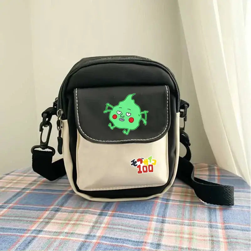 Black and cream reigen arataka canvas crossbody bag featuring green cartoon character with red cheeks on front flap
