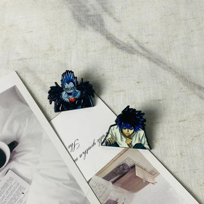 Two anime boy enamel pin bookmarks featuring death note characters ryuk and light yagami with blue hair and dark design