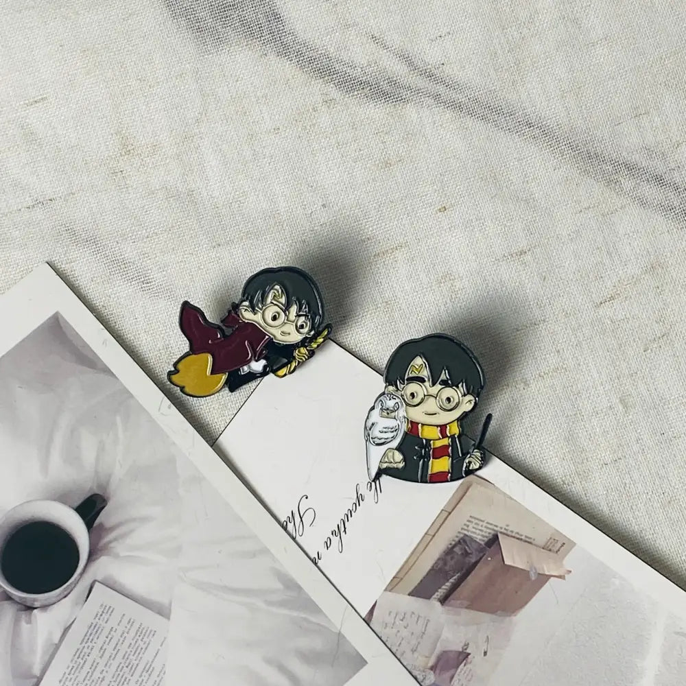 Two anime boy enamel pins featuring a flying boy in maroon robes with broomstick and holding an owl and wand