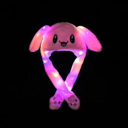 Pink soft plush bunny hat with glowing led ears and long crossed straps ending in paw-shaped feet for cosplay
