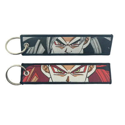 Two embroidered key fobs featuring anime faces with silver hair red eyes and white face paint green eyes key tags
