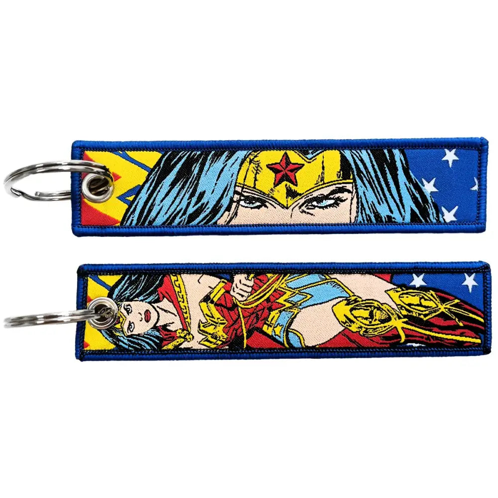 Two embroidered wonder woman key fobs with comic-style designs on blue fabric key tags with metal rings
