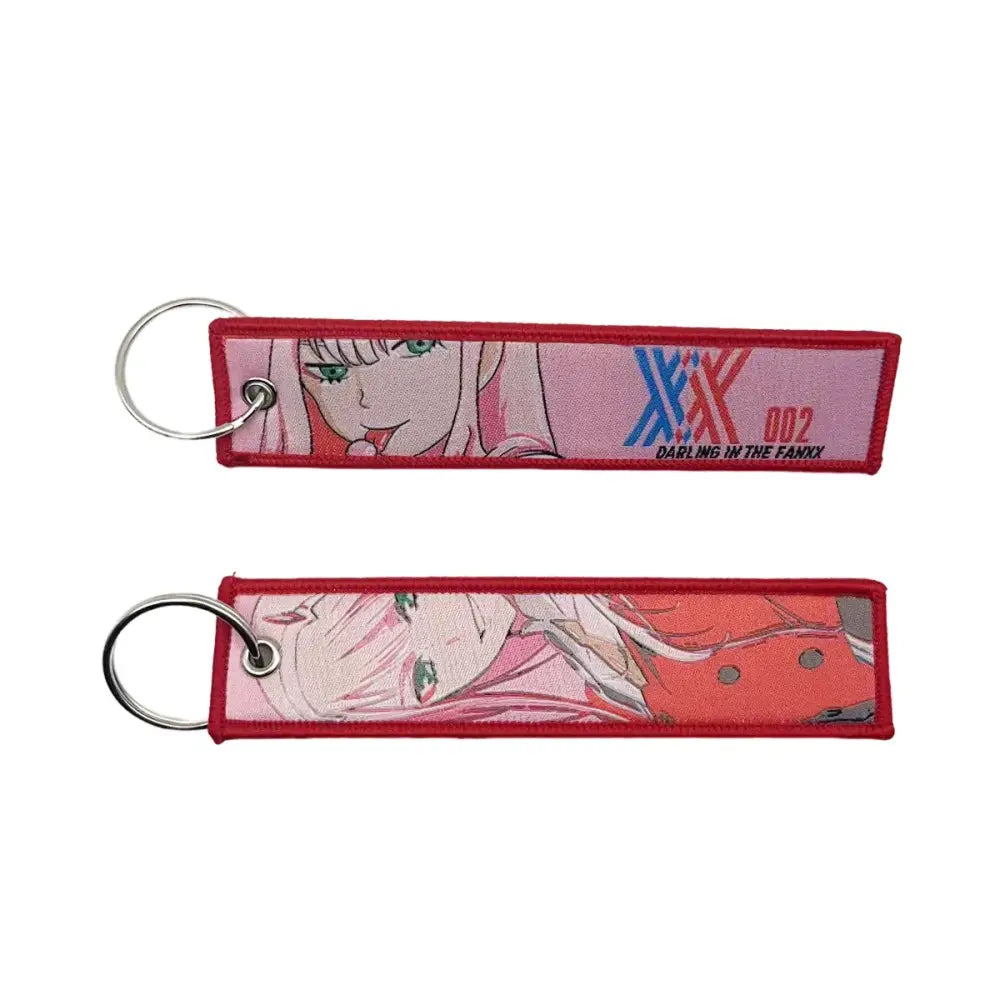 Red embroidered key fob featuring an anime character with pink hair green eyes and darling in the franxx logo key tag