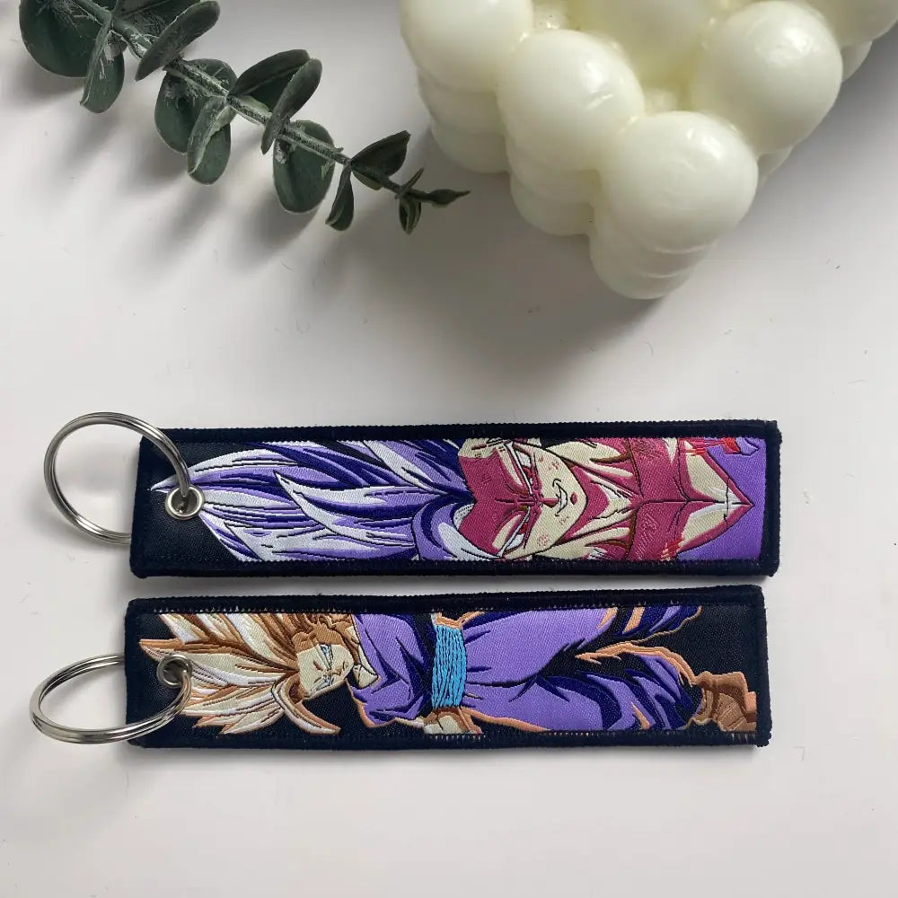 Two embroidered key fobs featuring anime characters in purple pink and gold blue tones key tag keychain