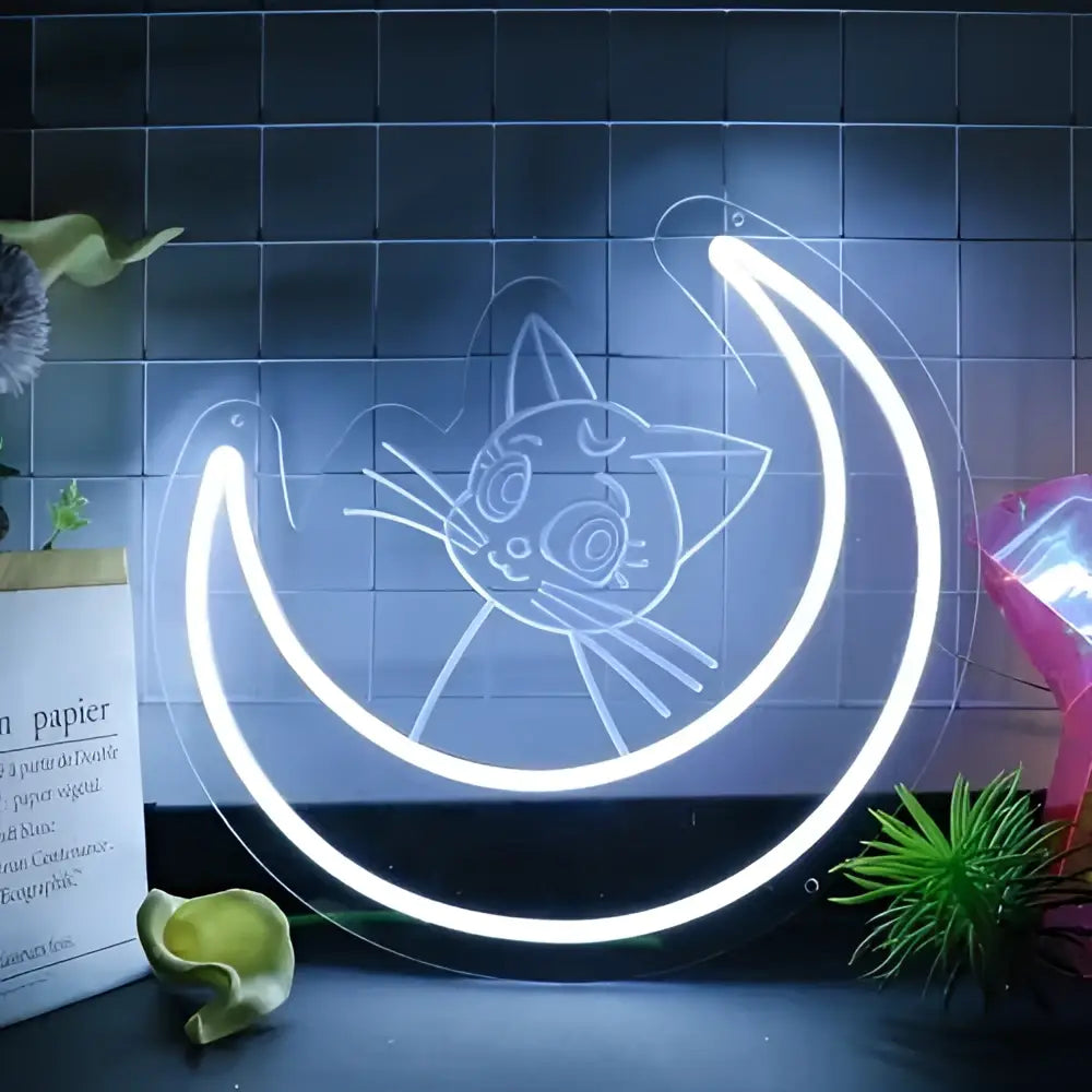 A glowing white led neon sign shaped like a crescent moon with an anime cat face etched in glass wall decor