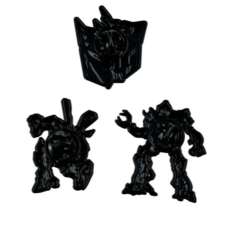 Black enamel pin set featuring three distinct transformers characters with glossy finish and detailed sculpted designs