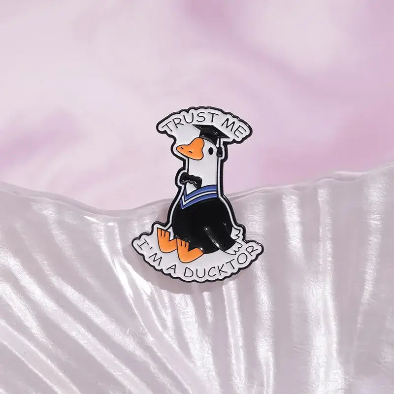 Black and orange graduation-themed anime character enamel pin metal brooch with trust me im a ducktor white lettering