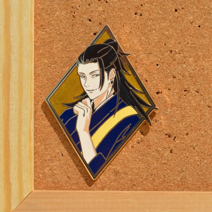 Diamond-shaped anime enamel pin featuring a character with long black hair in blue and yellow traditional outfit on gold background