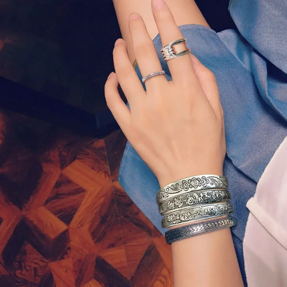Stacked silver-toned tibetan silver retro cuff bracelets with intricate floral and patterned engravings