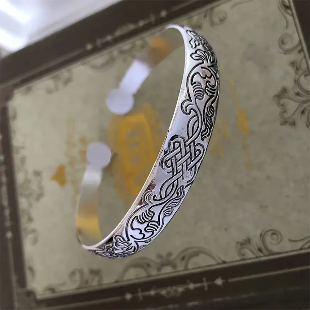 Anime-inspired retro cuff bracelet in tibetan silver with intricate black engraved swirling vines and knotwork patterns