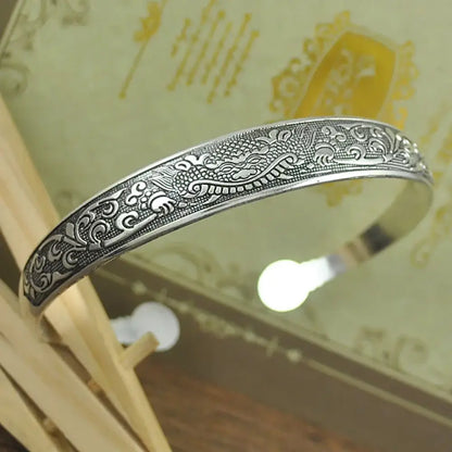 Silver dragon-themed tibetan silver retro cuff bracelet with intricate engraved patterns in carved metal design