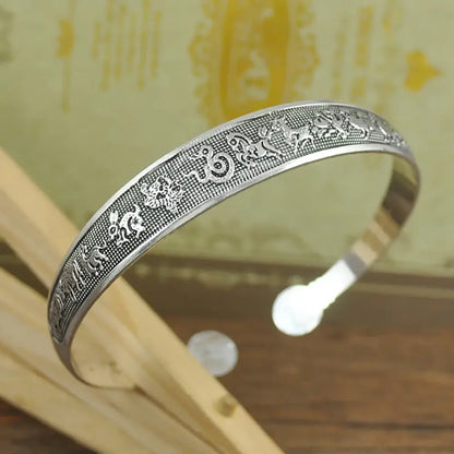 Silver tibetan silver retro cuff bracelet with intricate animal engravings and swirling motifs on textured surface