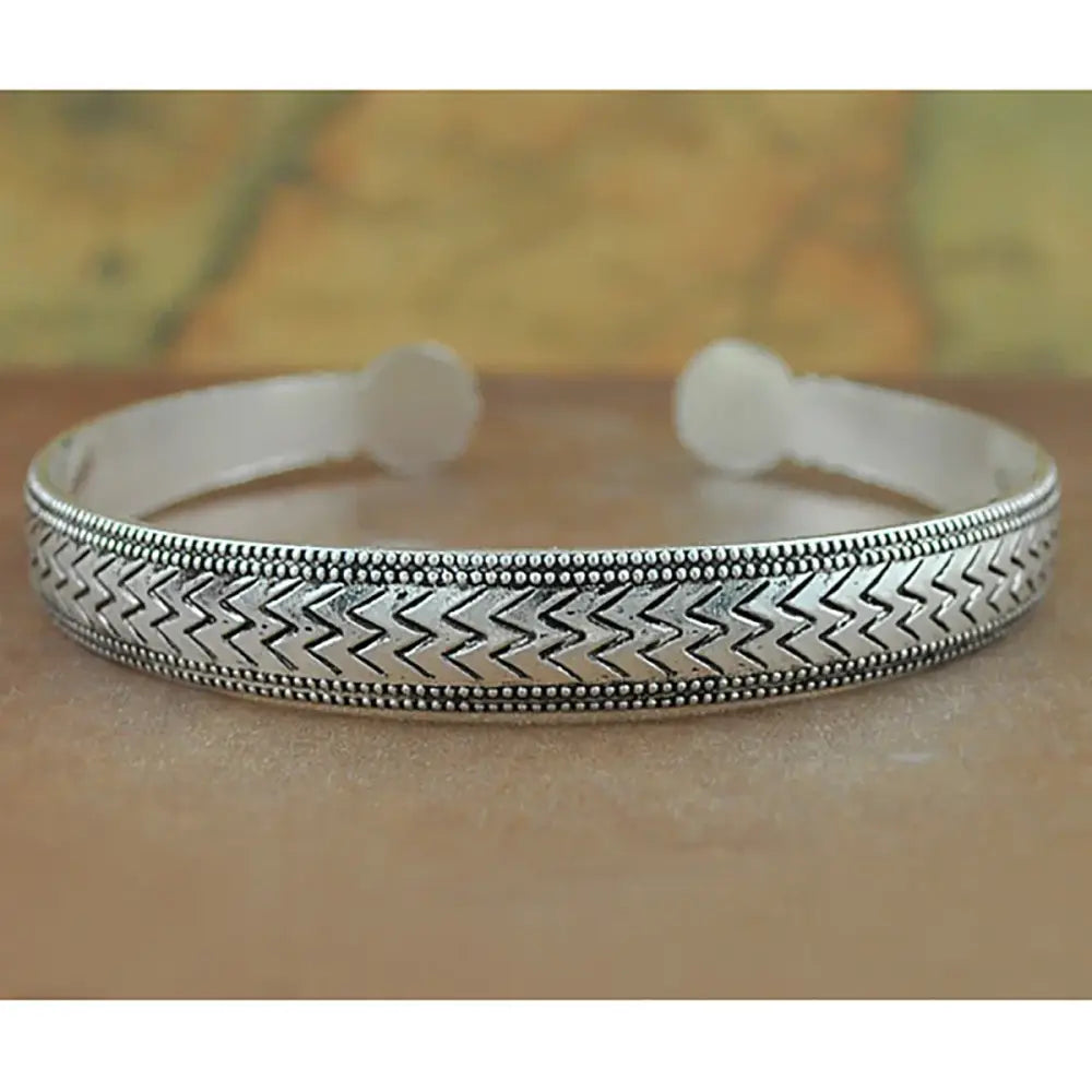 Silver-toned tibetan silver retro cuff bracelet with intricate zigzag pattern and beaded detailing on carved metal