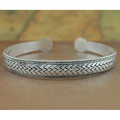 Silver-toned tibetan silver retro cuff bracelet with intricate zigzag pattern and beaded detailing on carved metal