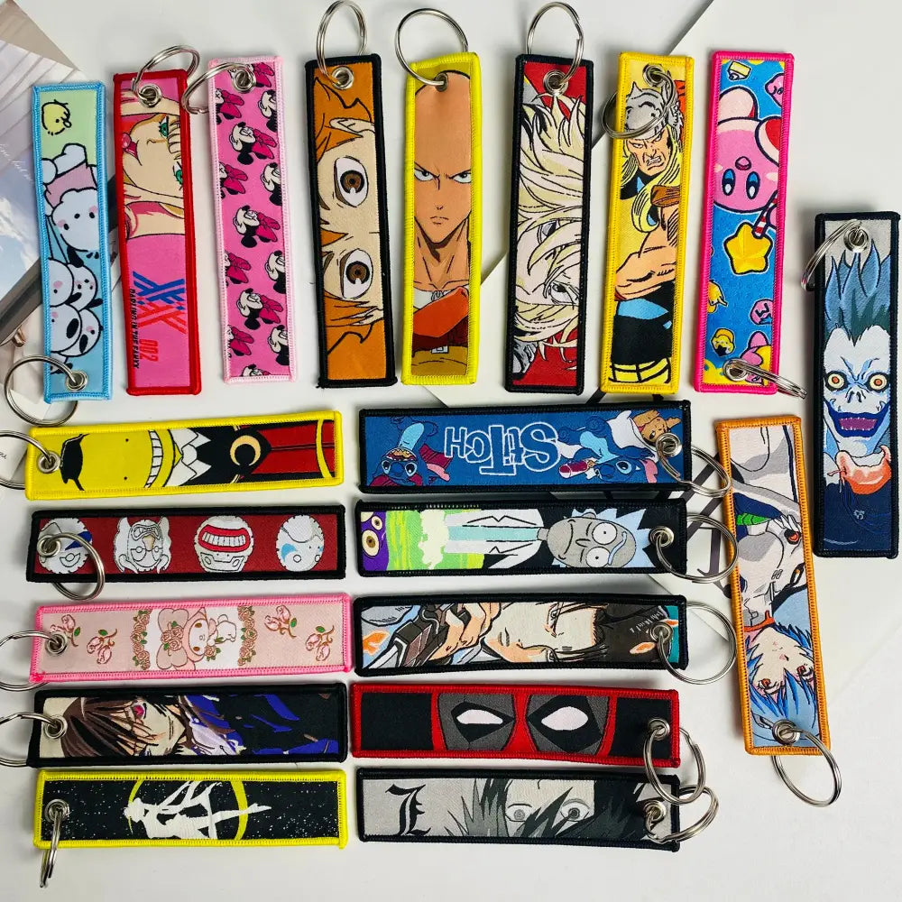 A collection of colorful embroidered anime lock keychain jet tags featuring various cartoon and anime characters