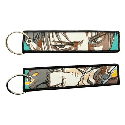 Two embroidered anime lock keychains with detailed character faces, black borders, and teal edges for jet tag use