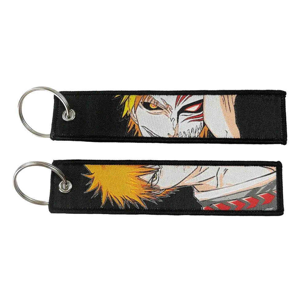 Black embroidered anime lock keychain featuring spiky yellow hair character and white mask on jet tag