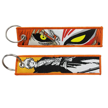 Orange embroidered anime lock keychain jet tag with vibrant yellow eyes and bold black and white artwork