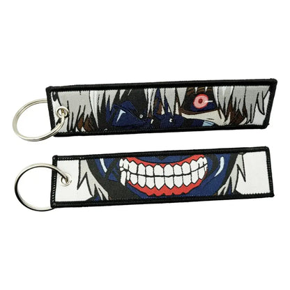 Two embroidered anime lock keychains featuring a white-haired figure with red eye and a grinning jet tag design