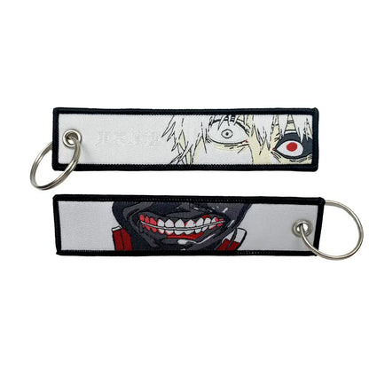 White embroidered anime lock keychain featuring black and red character designs with silver metal rings