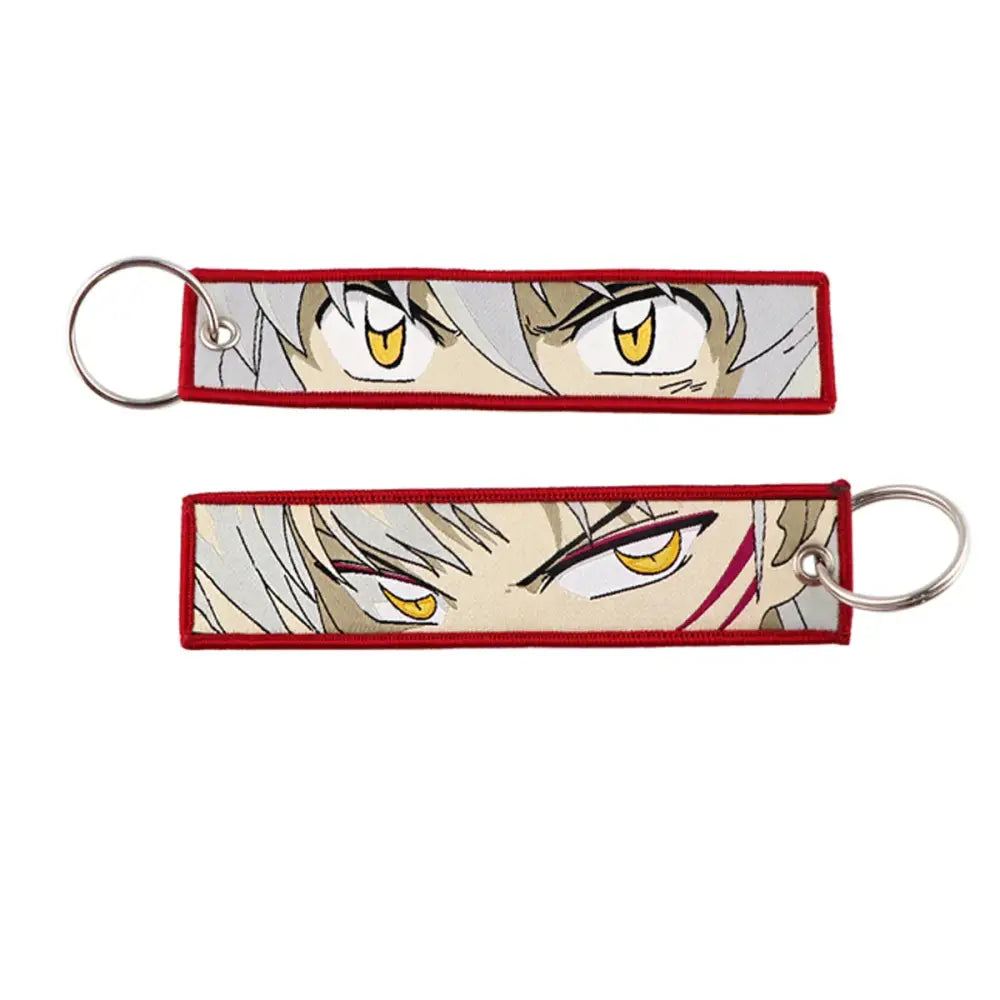 Red-bordered embroidered anime lock keychain with intense yellow eyes and silver hair jet tag design close-up