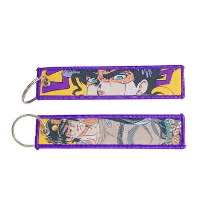 Two purple embroidered anime lock keychains featuring jojo’s bizarre adventure characters with metallic jet tag rings