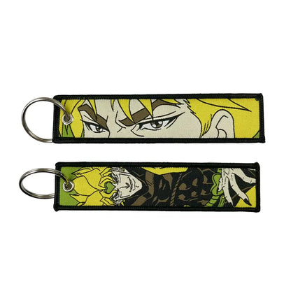Two embroidered anime lock keychains with vibrant yellow hair and black outlines on a bright green background