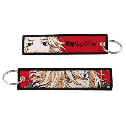 Red embroidered anime lock keychain featuring blonde anime character and japanese text on black-bordered jet tag fabric strip