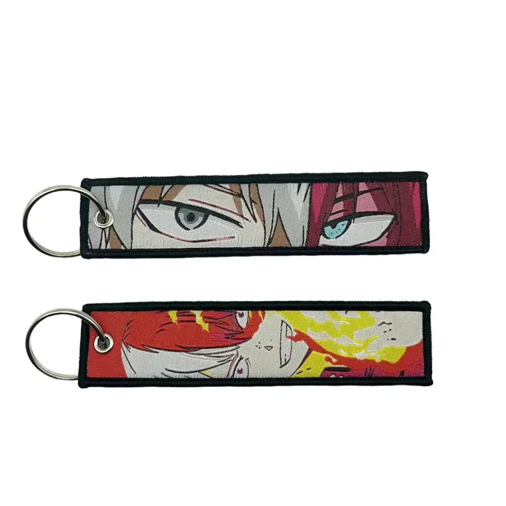 Two embroidered anime lock keychains featuring a white-haired character and red yellow action scene designs