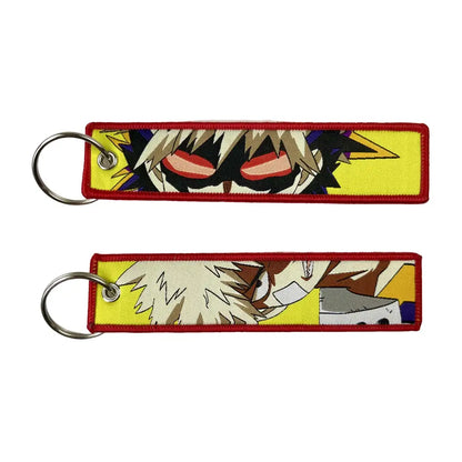 Two embroidered anime lock keychains with spiky hair characters on a bright yellow and red bordered background