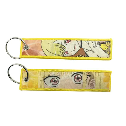 Yellow embroidered anime lock keychain featuring pink-eyed blonde hair character design on jet tag material