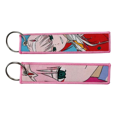 Pink embroidered anime lock keychain featuring character designs with metallic rings for secure attachment