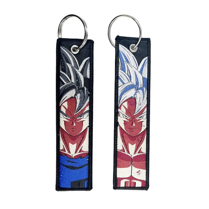 Two embroidered anime lock keychains with spiky hair designs in black silver and blue white on dark fabric background