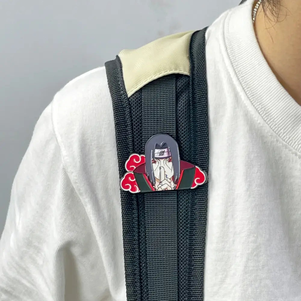 Glossy enamel pin of itachi uchiha in akatsuki cloak with red clouds manga enamel pin on black backpack strap