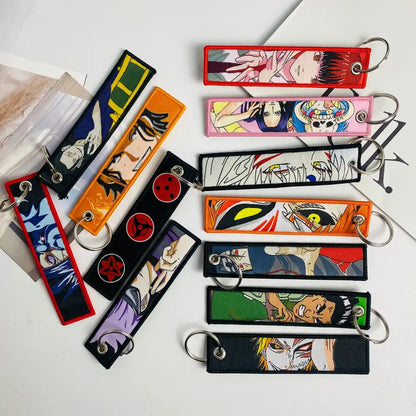A collection of colorful rectangular anime mix character jet tag keychains with embroidered designs and metal rings