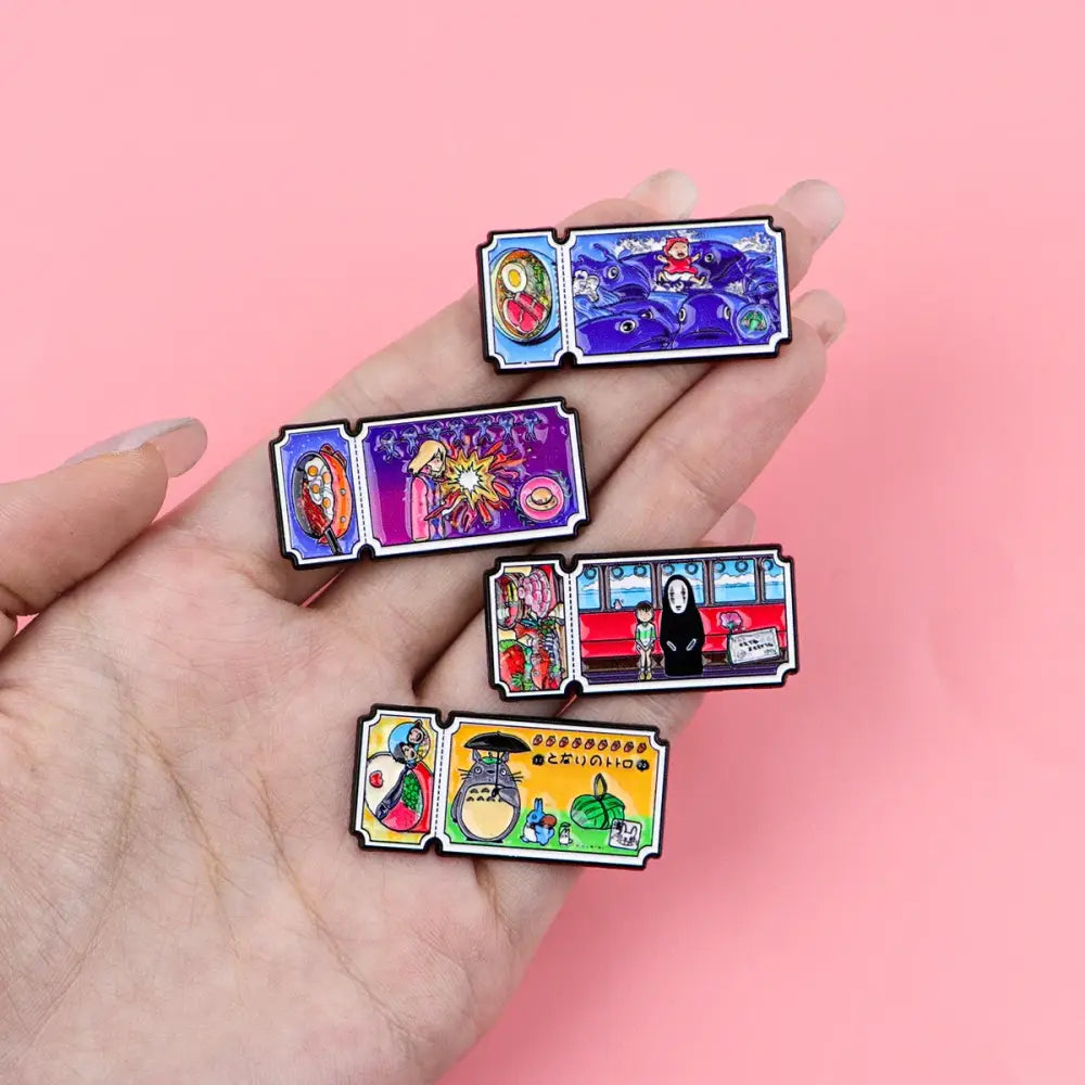 A hand holds four colorful rectangular enamel pins from the anime movie ticket cat enamel pin set