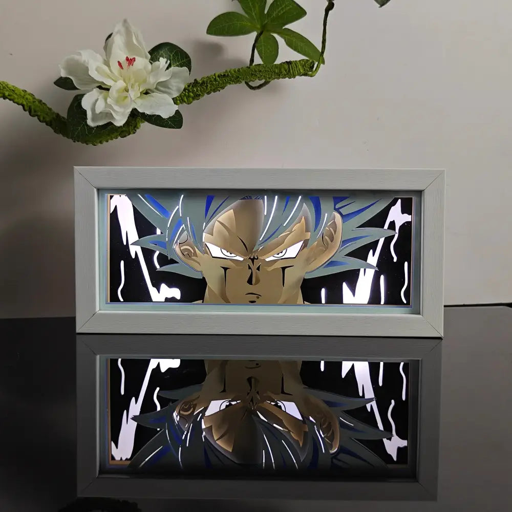 A glowing white-framed anime night light box featuring a blue and gold super saiyan goku paper-cutout for table decor