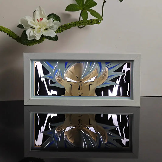 A glowing white-framed anime night light box featuring a blue and gold super saiyan goku paper-cutout for table decor