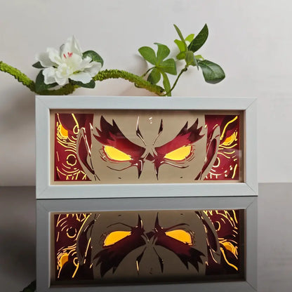 White-framed anime paper-cut led lamp with glowing yellow eyes red accents and 7-color remote control on beige background