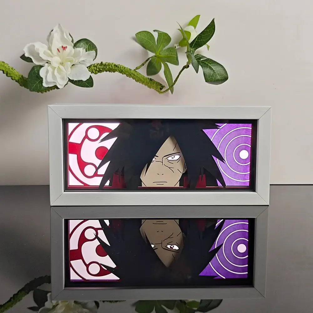 Silver-framed anime paper-cut led light box featuring madara uchiha with glowing red and purple circular patterns