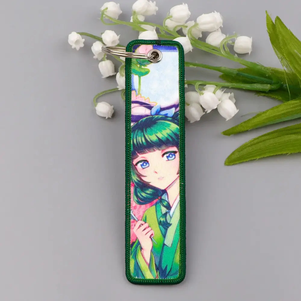Green embroidered metal maomao key chain featuring anime character with green hair and blue eyes in traditional attire key ring