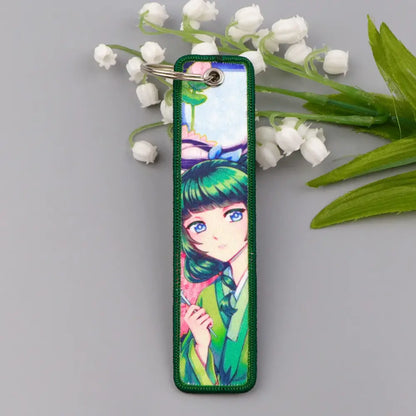 Green embroidered metal maomao key chain featuring anime character with green hair and blue eyes in traditional attire key ring