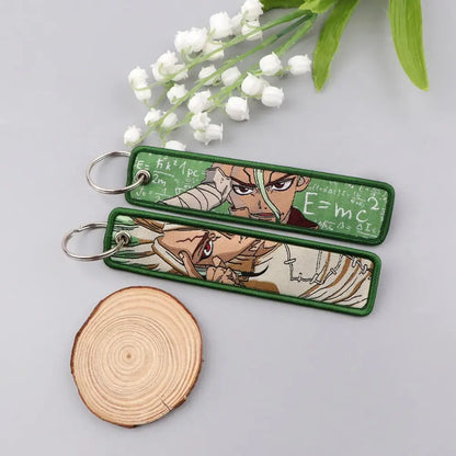 Green embroidered apothecary diaries maomao key chain with anime characters and math equations on fabric background