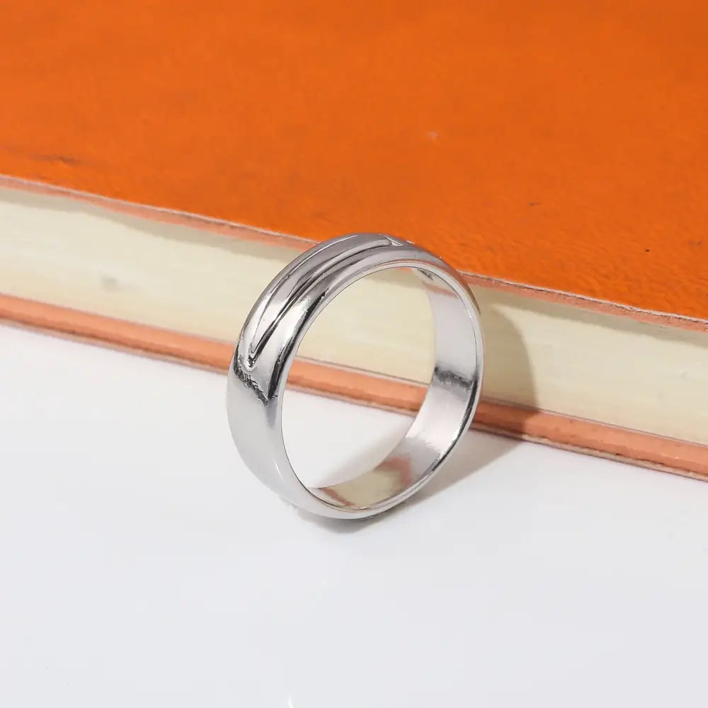 A sleek silver-toned annie leonhart ring with two parallel grooves in a modern minimalist wedding band design