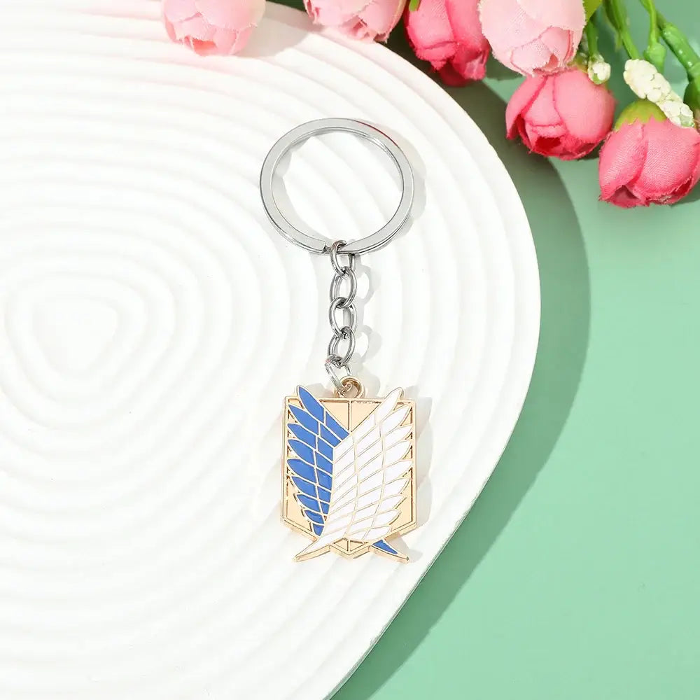 Metallic enamel pin keychain with a blue and white scout regiment winged emblem on a gold-toned shield pendant