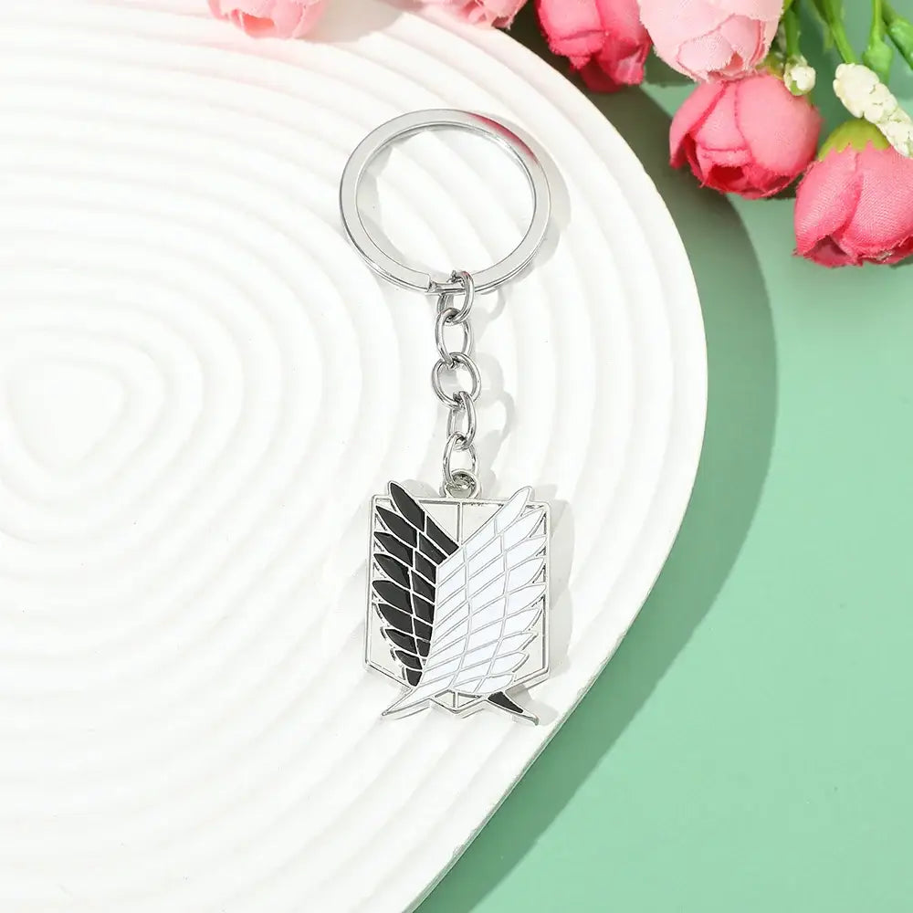 Silver metal enamel pin keychain featuring the scout regiment emblem with black and white detailing from attack on titan