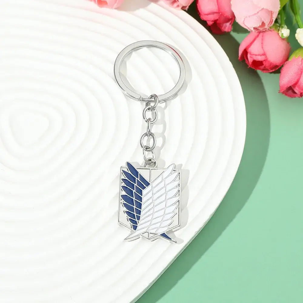 Silver metal scout regiment enamel pin keychain with blue and white detailing featuring attack on titan emblem