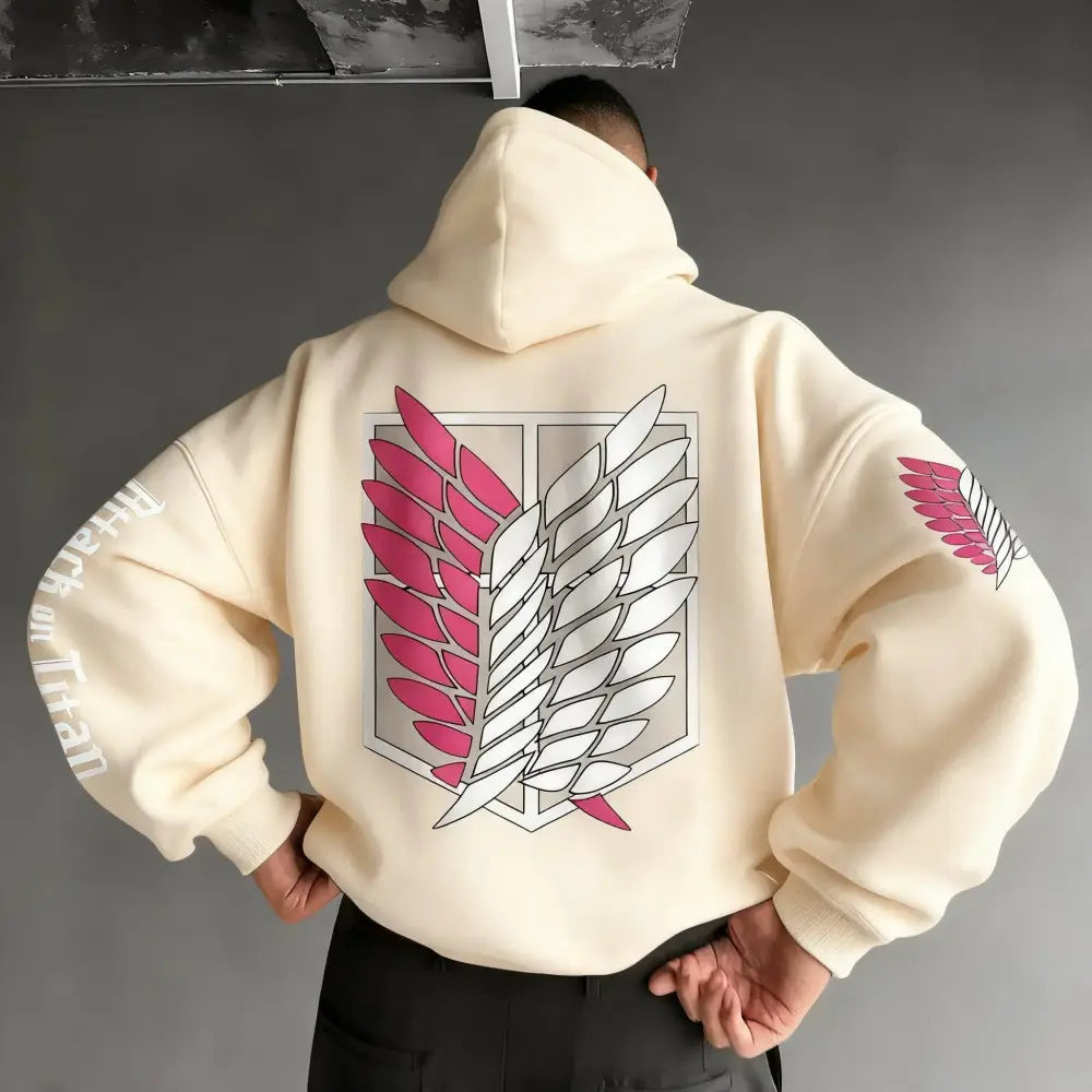 Back side of a cream-colored attack on titan wings oversized hoodie with pink and white winged emblem and sleeve patches