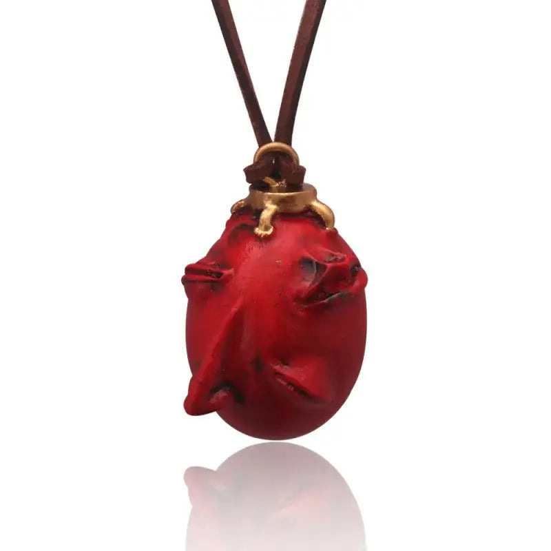 Glossy red hand-carved pig-shaped behelit pendant necklace made of zinc alloy on brown leather cord with gold clasps